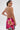A woman with a ponytail and hoop earrings poses with her back to the camera, wearing the WILD THANG PRINTED MINI DRESS featuring a bold zebra print and vivid pink lily design.