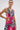 A woman wears the WILD THANG PRINTED MINI DRESS, featuring a sleeveless zebra print with bold pink tropical flowers. Her hair is tied back and she accessorizes with hoop earrings, standing against a plain white background.
