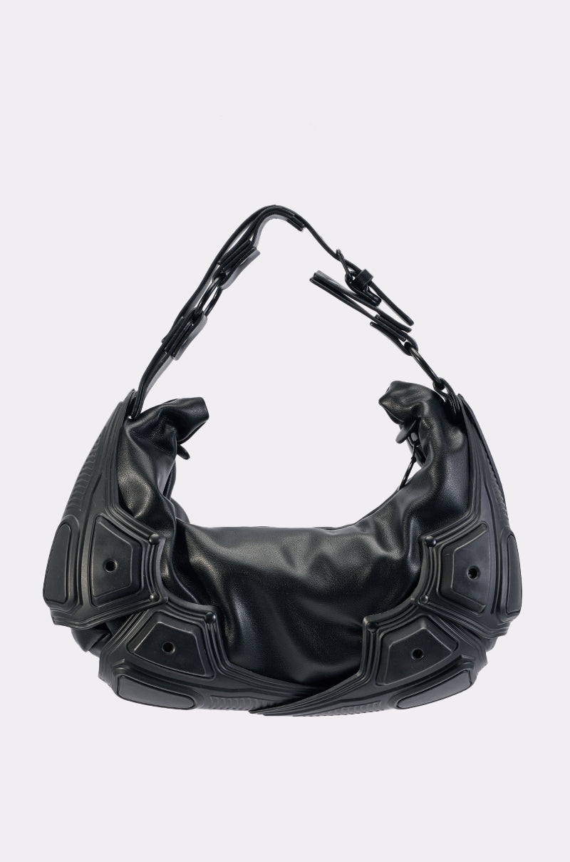 The KNOCKED OUT PURSE is a black faux leather handbag featuring geometric raised panel accents and a chunky, angular handle, offering a fresh take on the classic streetwear bag against a plain light background.