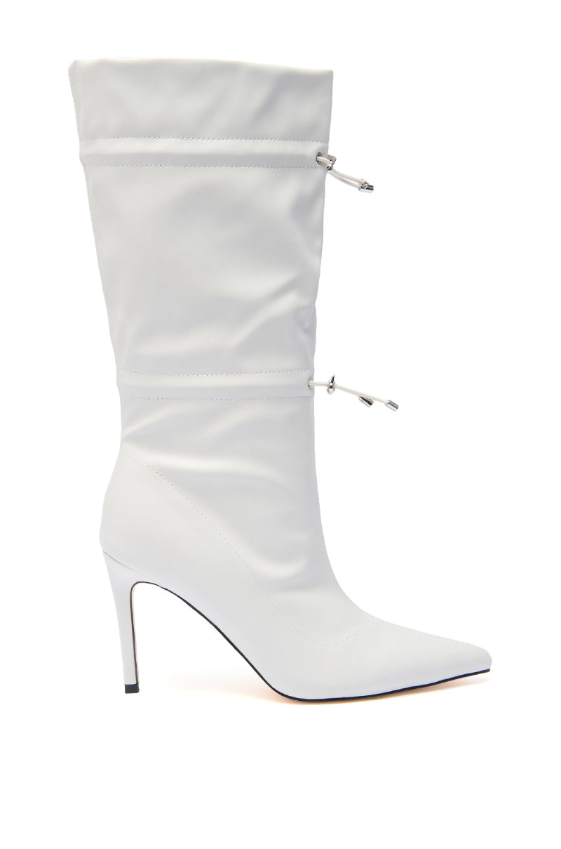 The AZALEA WANG SEANNA IVORY CINCHED STILETTO BOOTIE is a white faux leather knee-high boot featuring a pointed toe, high stiletto heel, and cinched drawstring details on the shaft. 1