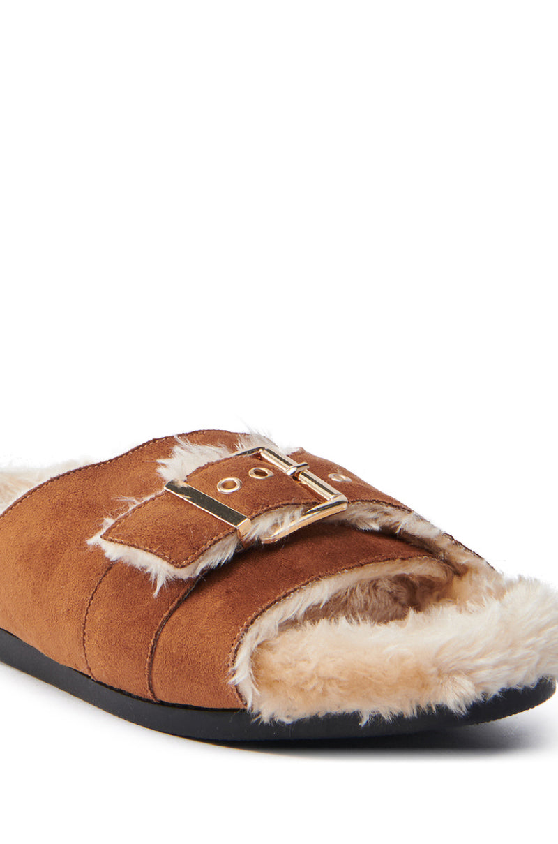 The AZALEA WANG SEANNA TAN FUR SANDAL is a brown faux suede slipper featuring a fluffy faux fur insole, an open almond toe, and a decorative gold buckle on the strap, with a contrasting black sole.