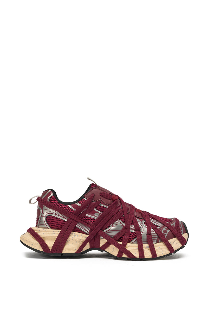 A side view of the AZALEA WANG SELIE BURGUNDY LACE UP SNEAKER, featuring a red mesh upper, red crisscrossing straps, silver accents, and a beige textured sole, shown against a plain white background. 2