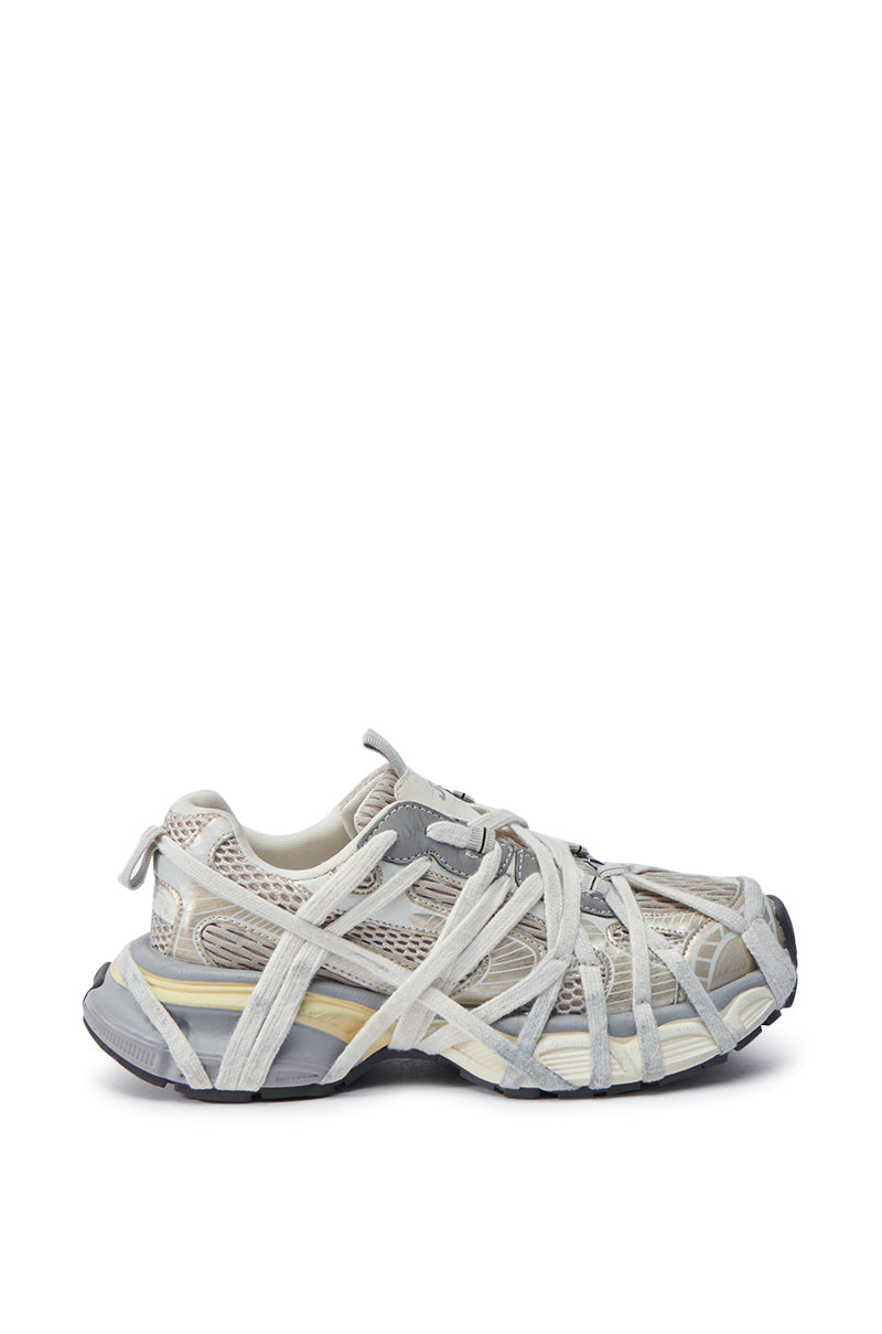 Introducing the AZALEA WANG SELIE WHITE FLAT SNEAKER, featuring a single gray and beige design with a distinctive crisscross strapping and textured rubber sole. This slip-on sneaker style masterfully combines mesh and leather materials for a modern, stylish appearance.
