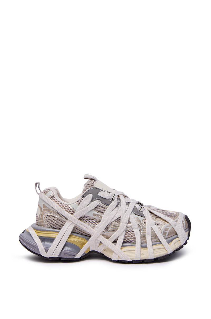 The AZALEA WANG SELIE WHITE FLAT SNEAKER features a light gray and beige design with chunky soles, distinctive white crisscross straps, and a layered, deconstructed look crafted from mesh, suede, and rubber.