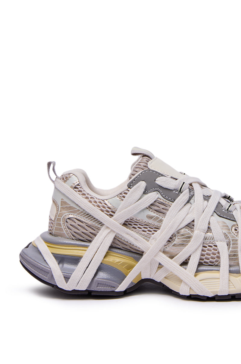 The AZALEA WANG SELIE WHITE FLAT SNEAKER features a chunky grey and beige mesh upper, metallic accents, thick white crisscross laces, and a bold layered sole in grey, beige, and yellow tones for standout style.