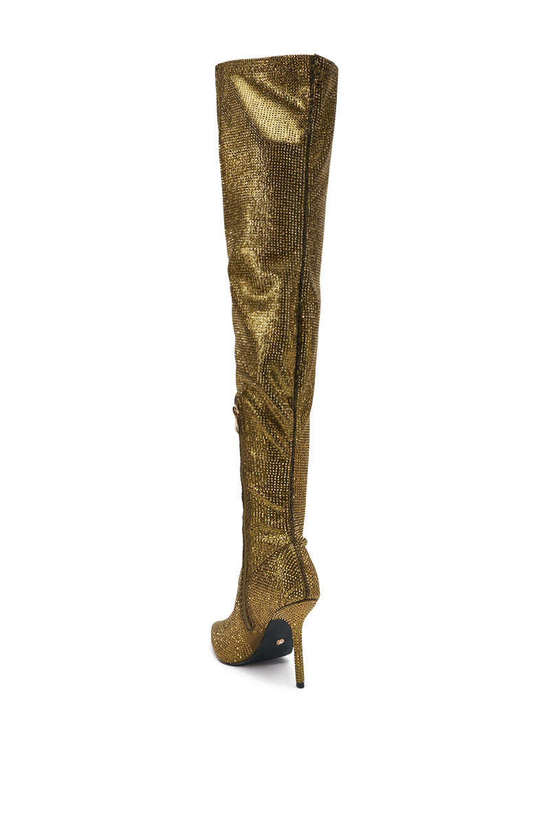 The AKIRA GOLD SELMA GOLD SPARKLE OVER THE KNEE BOOT features shimmering gold material, a high stiletto heel, and a side zipper—perfect for those who love glamorous statement boots.