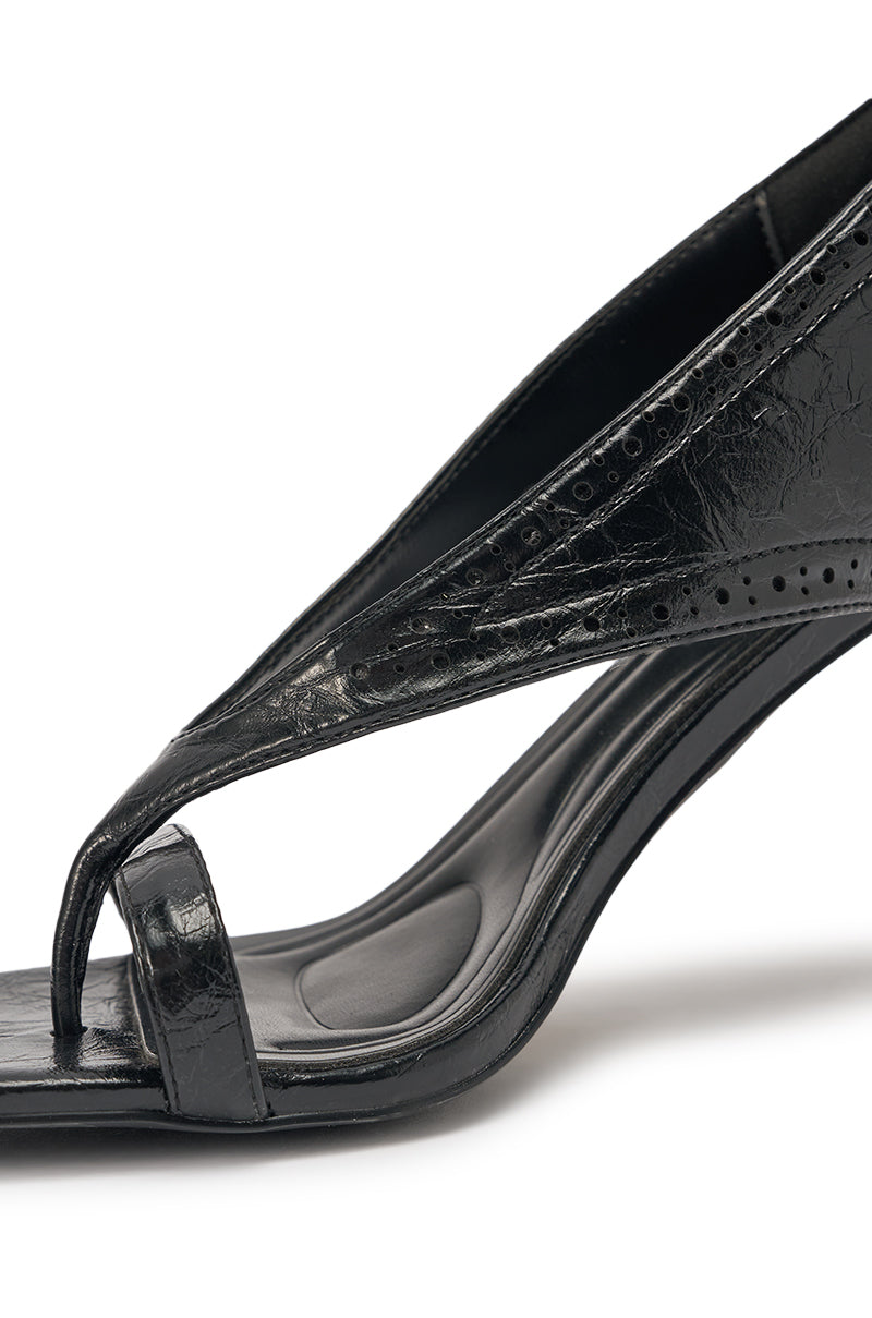 Close-up of the AKIRA GOLD SELVARE BLACK THONG STILETTO SANDAL, a black faux leather stiletto with an open square toe, toe strap, and textured perforated upper, shown against a white background. 6
