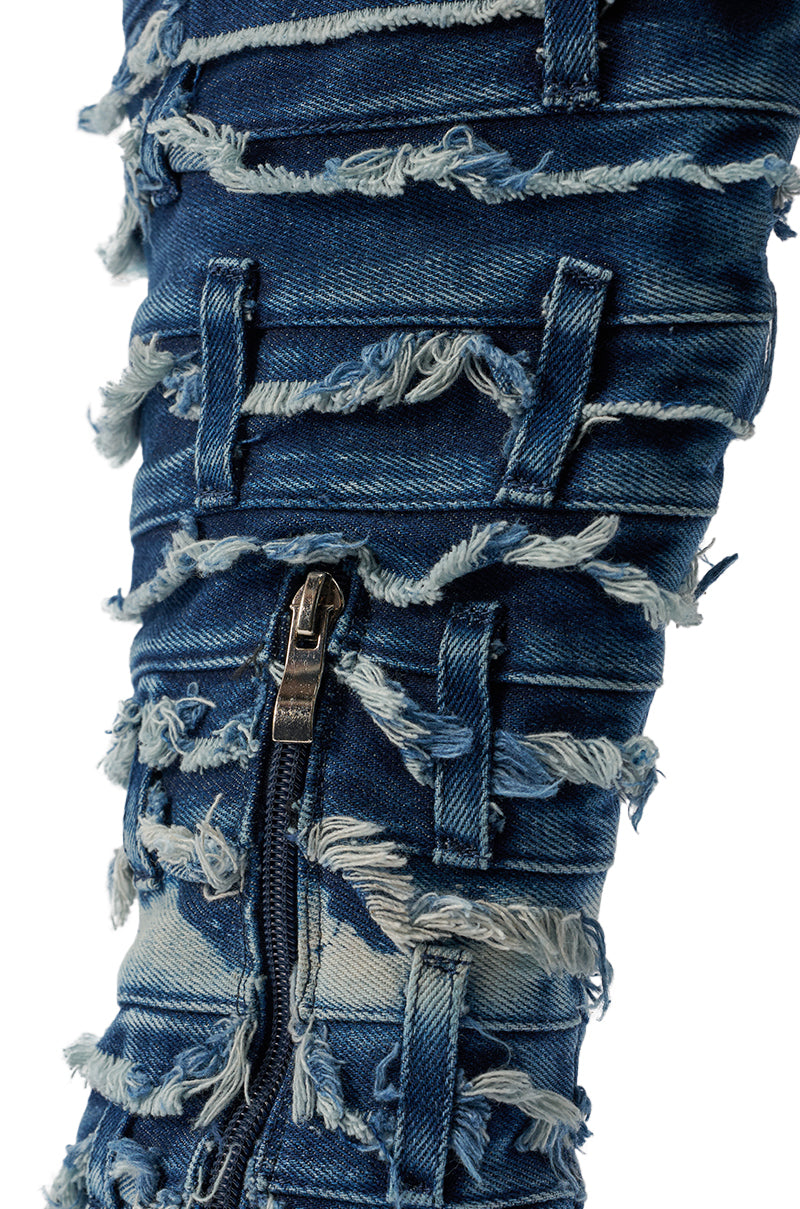 A close-up of distressed denim with frayed patches, horizontal strips, and a silver zipper from the AZALEA WANG SENA DENIM STILETTO OPEN TOE BOOT. 7
