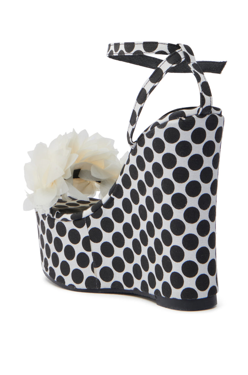 The AZALEA WANG SERAIAH BLACK AND WHITE POLKA DOT WEDGE SANDAL boasts a playful polka dot pattern and secure ankle strap, adorned with 3D tulle floral appliques near the toe for a stylish and unique look.