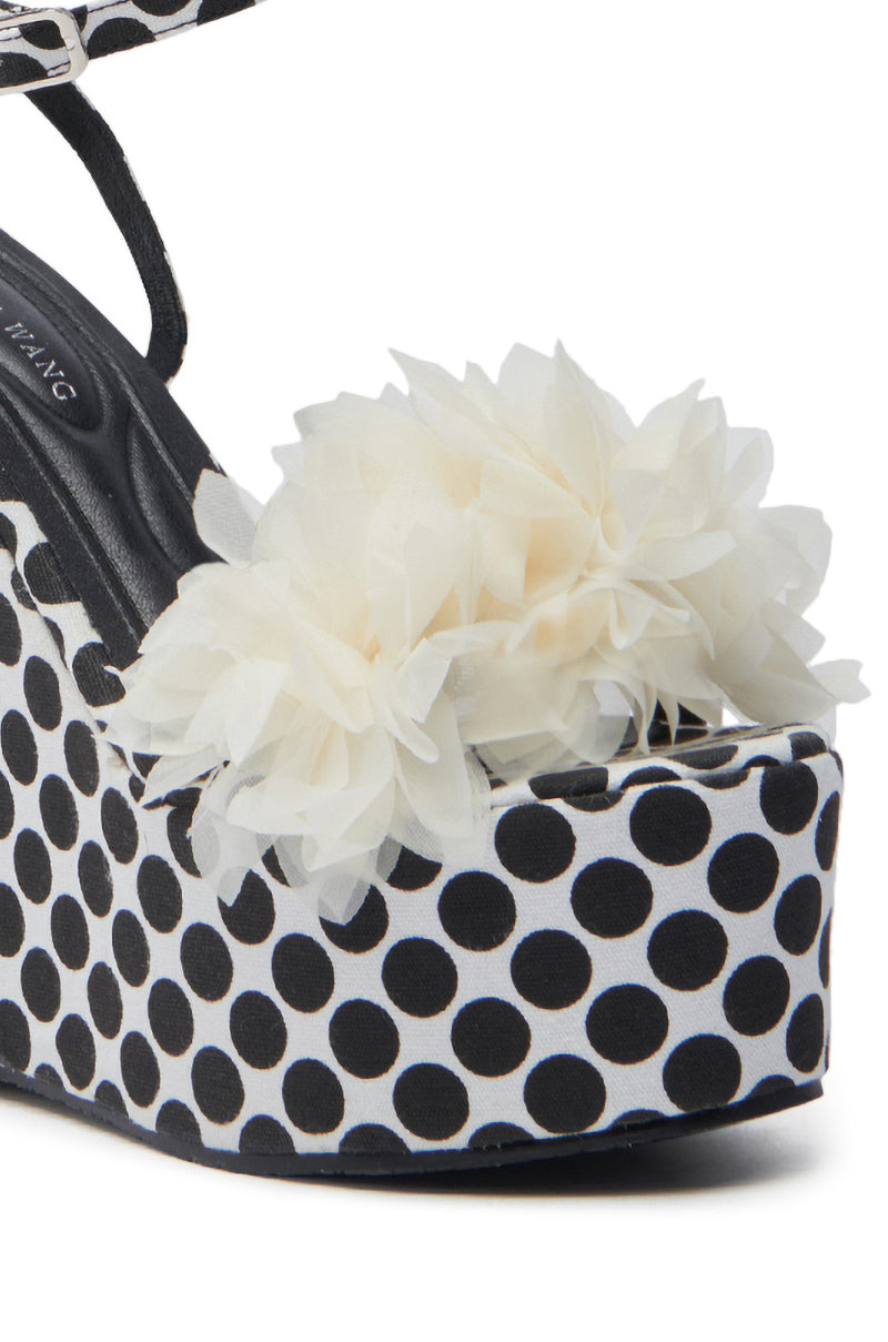 The AZALEA WANG SERAIAH BLACK AND WHITE POLKA DOT WEDGE SANDAL features a striking polka dot pattern with 3D tulle floral appliques, complemented by a black insole and platform sole, delivering both height and flair to your look.
