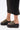 A person in a black midi skirt and AZALEA WANG SERGO BLACK EMBELLISHED CHUNKY SANDAL with a platform sole and multiple gold studs stands on a white background.