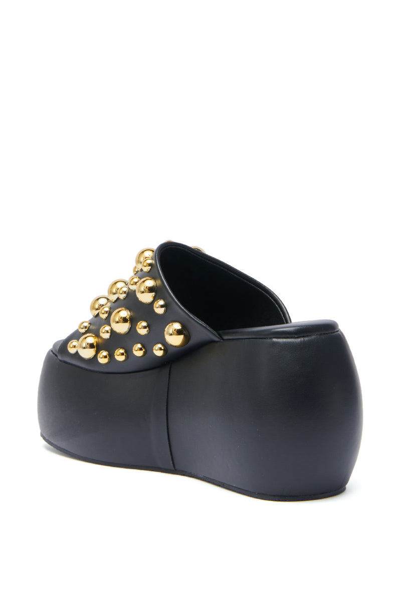 The AZALEA WANG SERGO BLACK EMBELLISHED CHUNKY SANDAL is a black faux leather, closed-toe platform clog featuring shiny gold studs, a chunky silhouette, and a sleek matte finish.