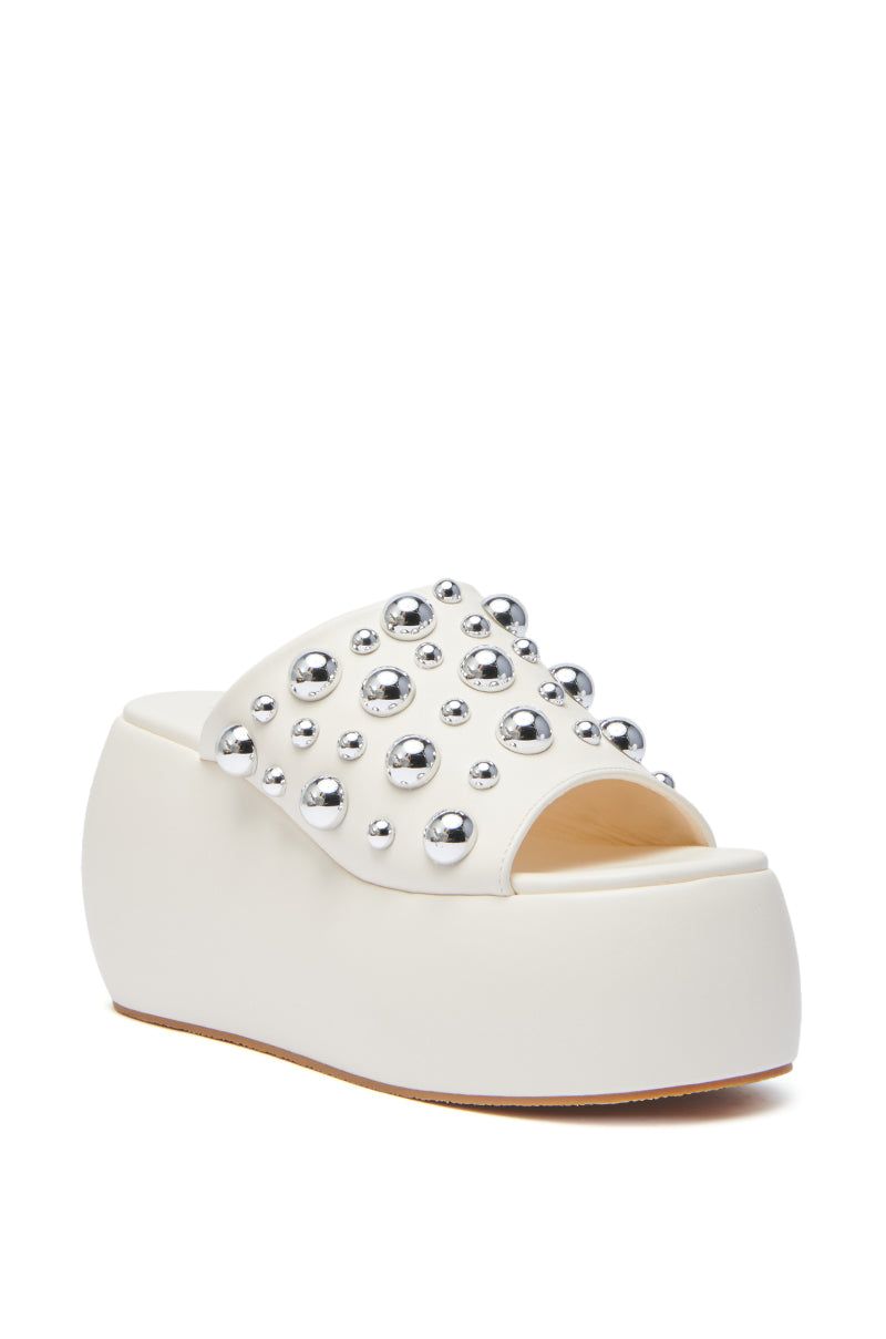 The AZALEA WANG SERGO BONE EMBELLISHED CHUNKY SANDAL is a white faux leather platform slide with an open toe and a wide upper strap adorned with silver studs, making it a standout addition to any look.
