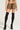 A person wearing the FIERCE CHEETAH MINI SKIRT paired with a matching top, black thigh-high socks, and black platform shoes is standing against a plain background. The image is cropped above the shoulders.