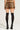 With their back to the camera, a person showcases the FIERCE CHEETAH MINI SKIRT with a matching top. They sport black knee-high socks and chic platform heels, all set against a plain, light background.
