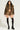 Dressed in a furry jacket, the FIERCE CHEETAH MINI SKIRT, and bubble hem shorts, paired with black knee-high socks and platform shoes, a person stands confidently against a plain background. The ensemble effortlessly merges bold patterns and textures.