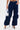 A person wearing navy blue FEEL GOOD TROUSER with cargo pockets, white pointed-toe heels, and holding a small metallic silver handbag. The photo is cropped from mid-torso to feet.