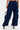 A person is shown from the back wearing FEEL GOOD TROUSER navy wide-leg cargo pants with a high-rise elastic waistband and cargo pockets, paired with white high-heeled shoes and holding a small transparent handbag.