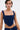 A person with short dark hair, facial piercings, and tattoos wears a fitted FEELING GOOD CORSET featuring sleek, lightweight fabric and a square neckline. The background is plain white.