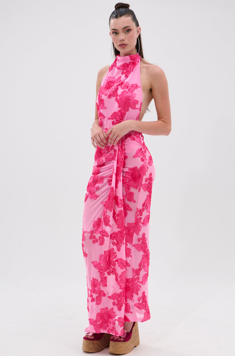 A woman poses against a white background with her hair pulled back, wearing the FLOWER GIRL MESH BODYSUIT, which features a sleeveless halter neckline and bold red floral patterns. 4