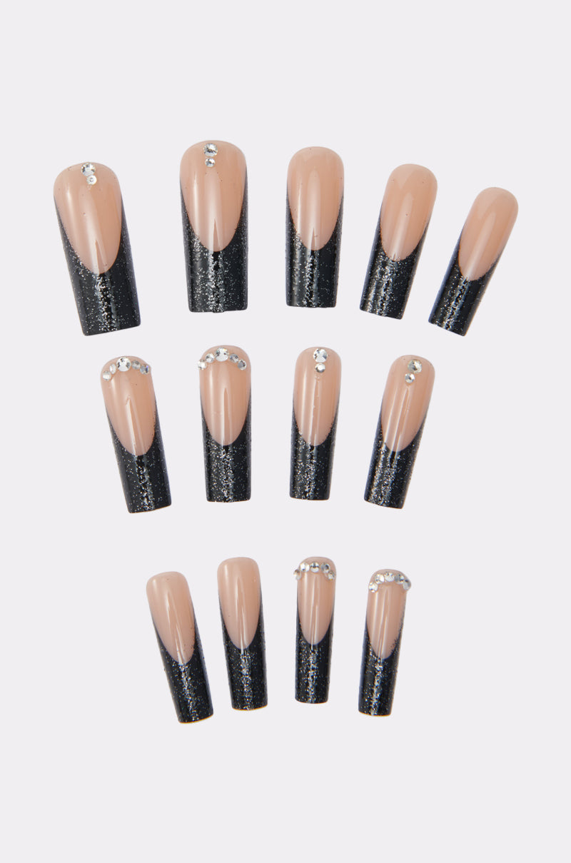 BLACK CAT FALSE NAILS feature a nude base, black glitter tips, and rhinestone accents near the cuticle, all elegantly arranged against a plain light background.