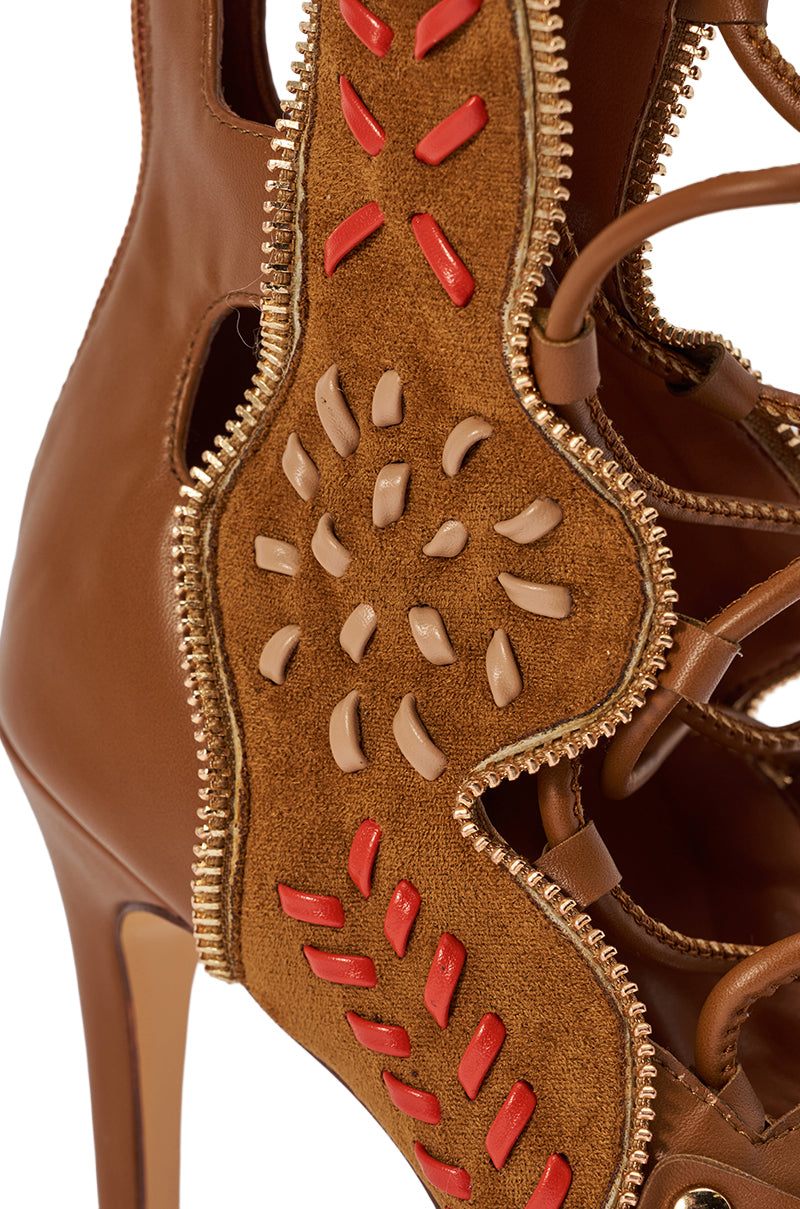 Close-up of the AZALEA WANG SHAI TAN GLADIATOR STILETTO SANDAL in brown leather and suede, with decorative stitching, raised tan and red accents, and gold zipper trim along the edges. 8