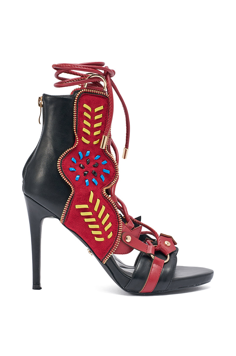 The AZALEA WANG SHAINIA BLACK MULTI SUEDE STILETTO SANDAL features a black base, red straps, lace-up ankle ties, gold-tone hardware, and a decorative side panel with red, yellow, blue, and gold accents. 2