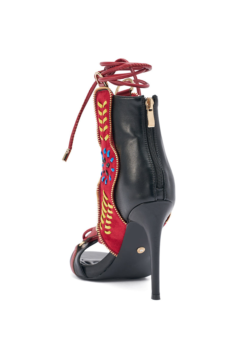 The AZALEA WANG SHAINIA BLACK MULTI SUEDE STILETTO SANDAL features a black suede base, red and yellow embroidery, blue accents, back zipper, comfort insole, and red ankle wrap laces against a white background. 4