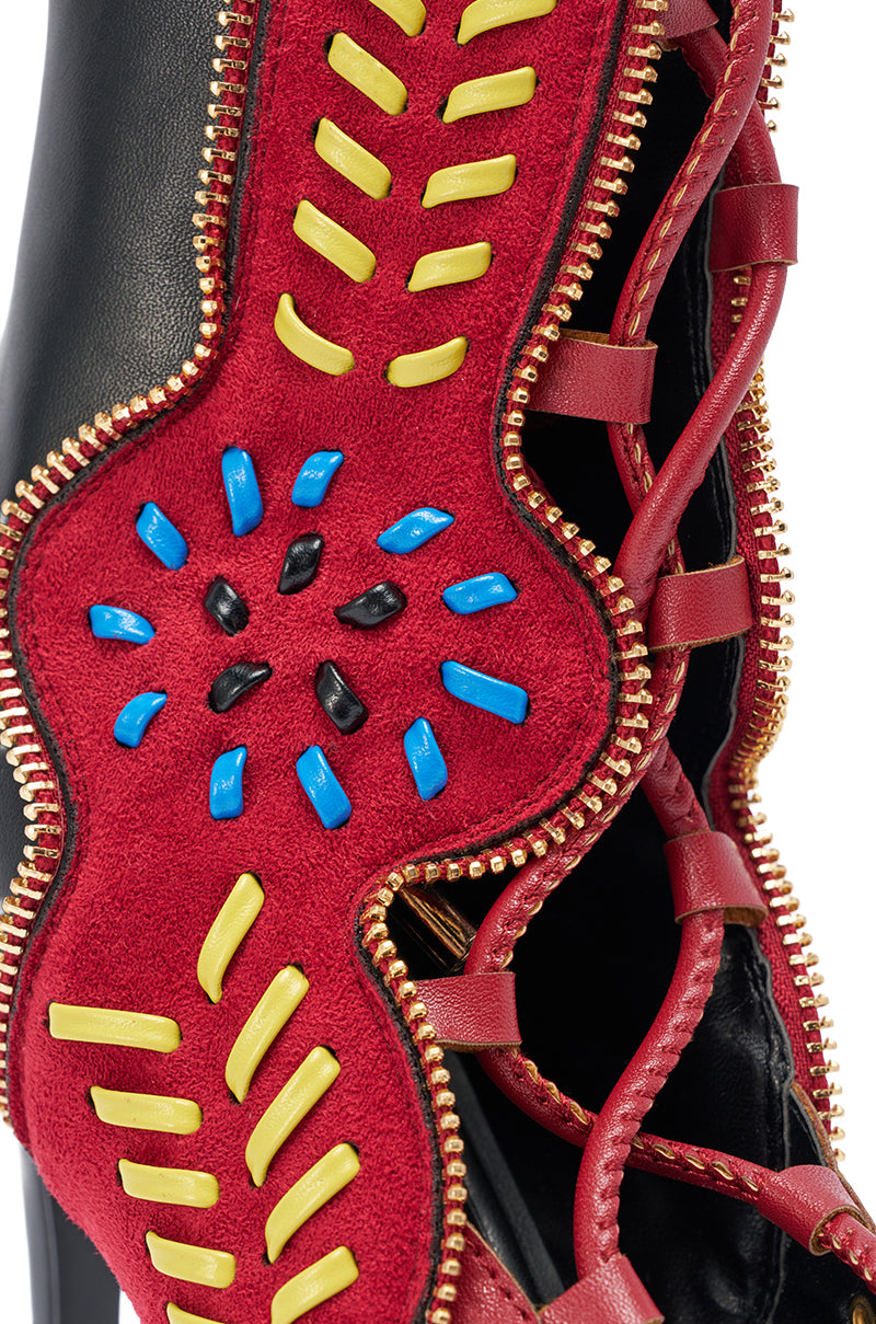 Close-up of the AZALEA WANG SHAINIA BLACK MULTI SUEDE STILETTO SANDAL, featuring red suede, yellow, blue, and black stitching, black leather accents, gold zipper trim, and red laces. Intricate details showcase bold artistry in this vibrant stiletto sandal. 5
