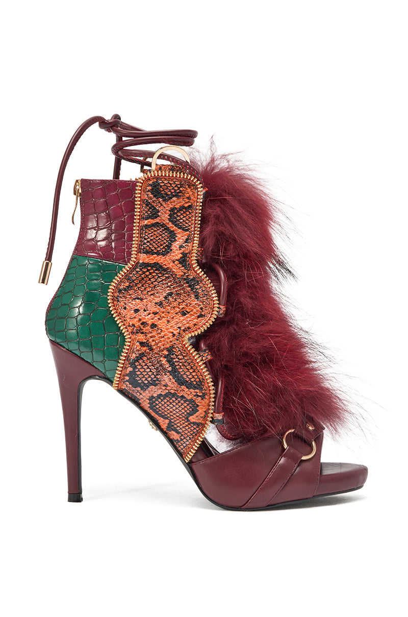 The AZALEA WANG SHAINY SNAKE BURGUNDY MULTI is a chic snakeskin stiletto sandal with burgundy, green, and orange textures, gold zipper detail, maroon faux fur trim, a lace-up ankle strap, open toe design, and bold burgundy stiletto heel. 2