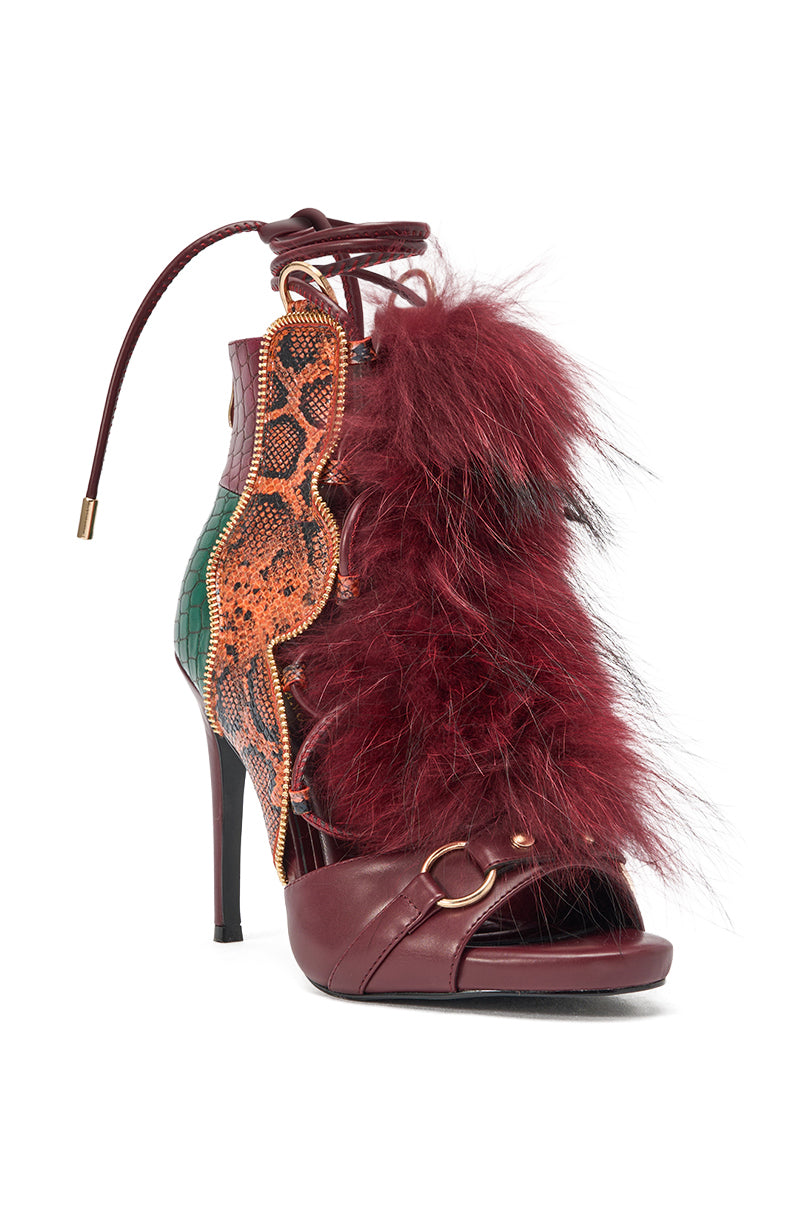 The AZALEA WANG SHAINY SNAKE BURGUNDY MULTI is a high-heeled sandal with a leather base, gold buckle, red faux fur front, orange snakeskin-patterned sides, lace-up ankle straps, and green textured accents. 3