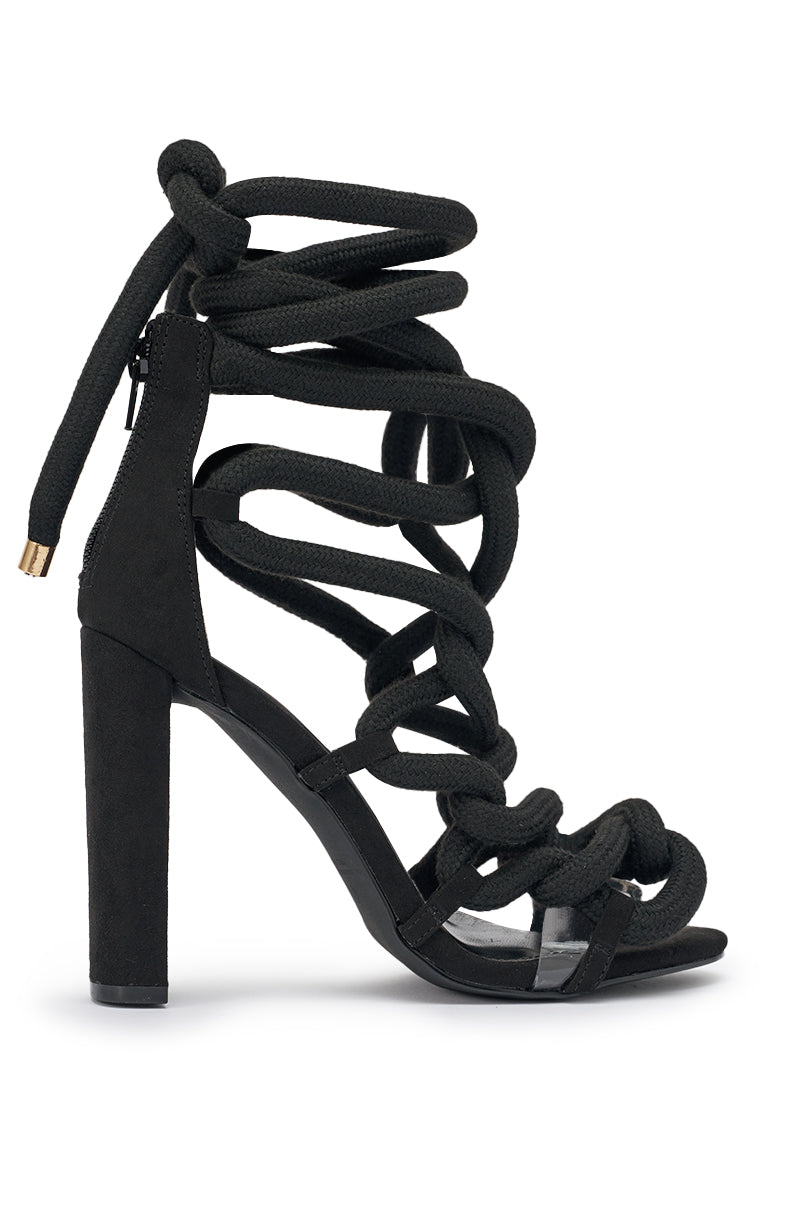 The AKIRA Gold Black Rope Strap Stiletto Sandal features black suede, thick rope-like lace-up straps, a stiletto heel, and an open-toe design for a bold modern look. 4