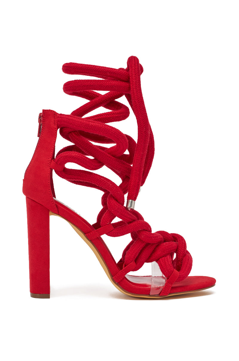 The AKIRA GOLD RED ROPE STRAP SANDAL is a striking red heel with thick, twisted rope straps that wrap up to the ankle, a closed heel, and clear accents over the toes. 4