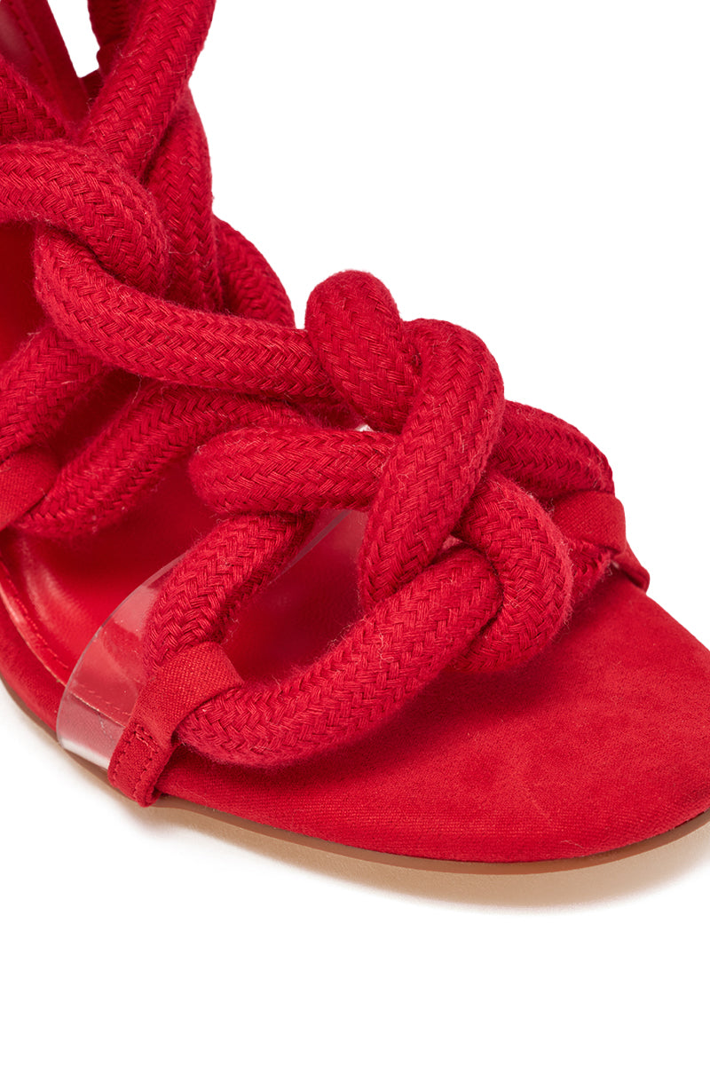 Close-up of the AKIRA GOLD RED ROPE STRAP SANDAL: features bold red braided fabric straps tied in knots, a transparent side strap, and a red suede sole for an elegant open-toe look. 7