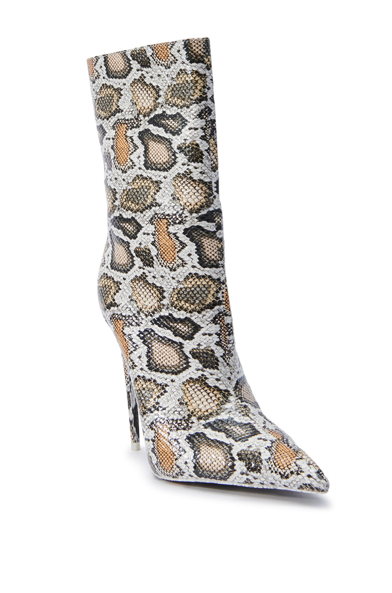 The AZALEA WANG SIBYLLE BEIGE SNAKE COCKTAIL BOOTIE features a chic and sleek mid-calf design with a pointed toe, flaunting a faux snakeskin pattern in shades of brown, black, and white. It's elegantly perched on a slim stiletto heel.