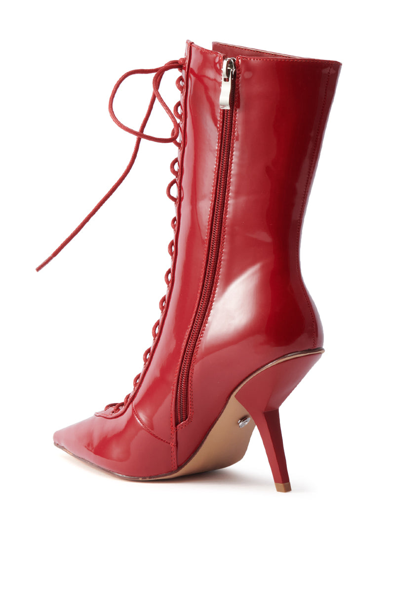The AZALEA WANG SILVA RED LACE UP STILETTO BOOTIE features a shiny red finish, lace-up front, pointed toe, sculptural stiletto heel, and side zipper, shown against a white background.