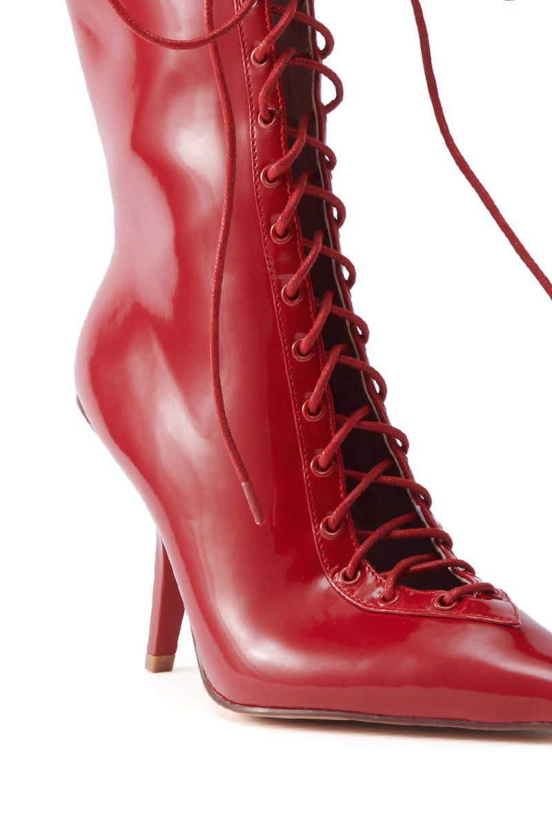 The AZALEA WANG SILVA RED LACE UP STILETTO BOOTIE features shiny red patent leather, a lace-up front, pointed toe, and sculptural heel, shown against a white background.