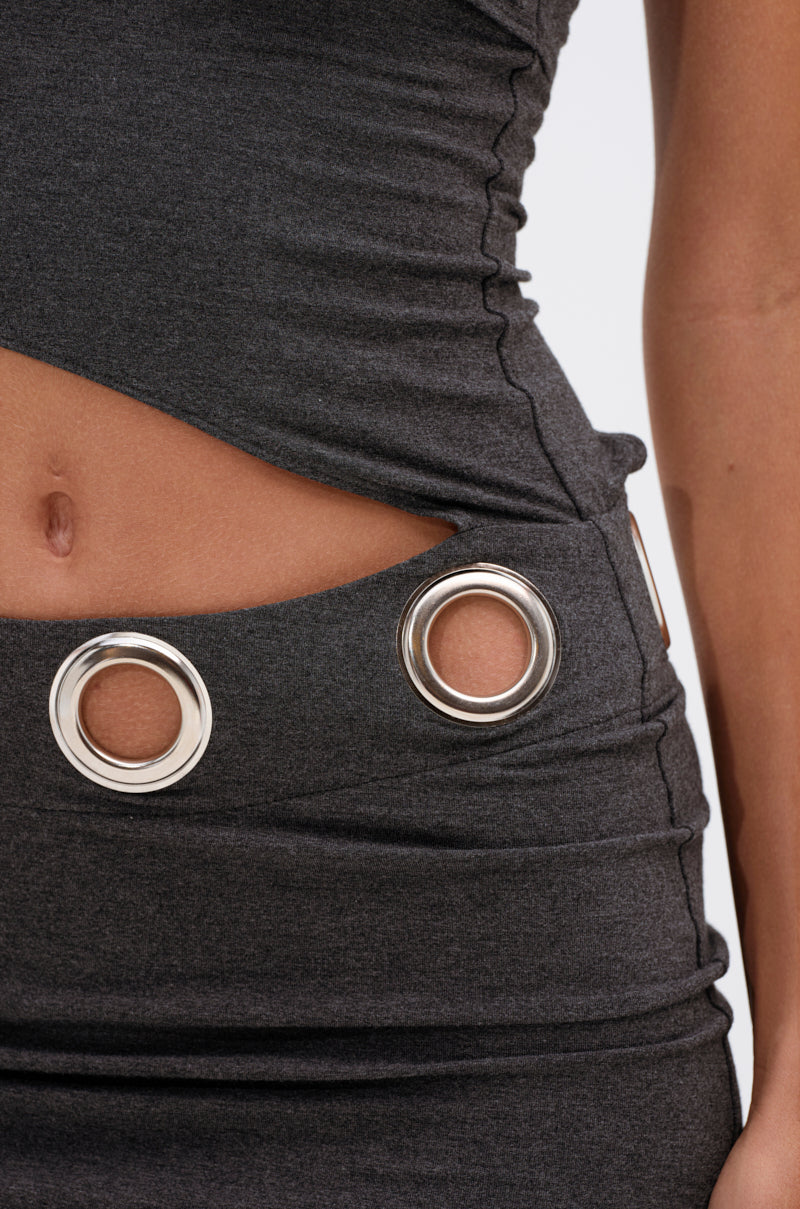 A close-up shows the torso and part of one arm wearing the ONE OF A KIND CUTOUT MINI DRESS, featuring an asymmetrical silhouette, dark gray fabric, waist cut-outs, and bold silver grommet details.