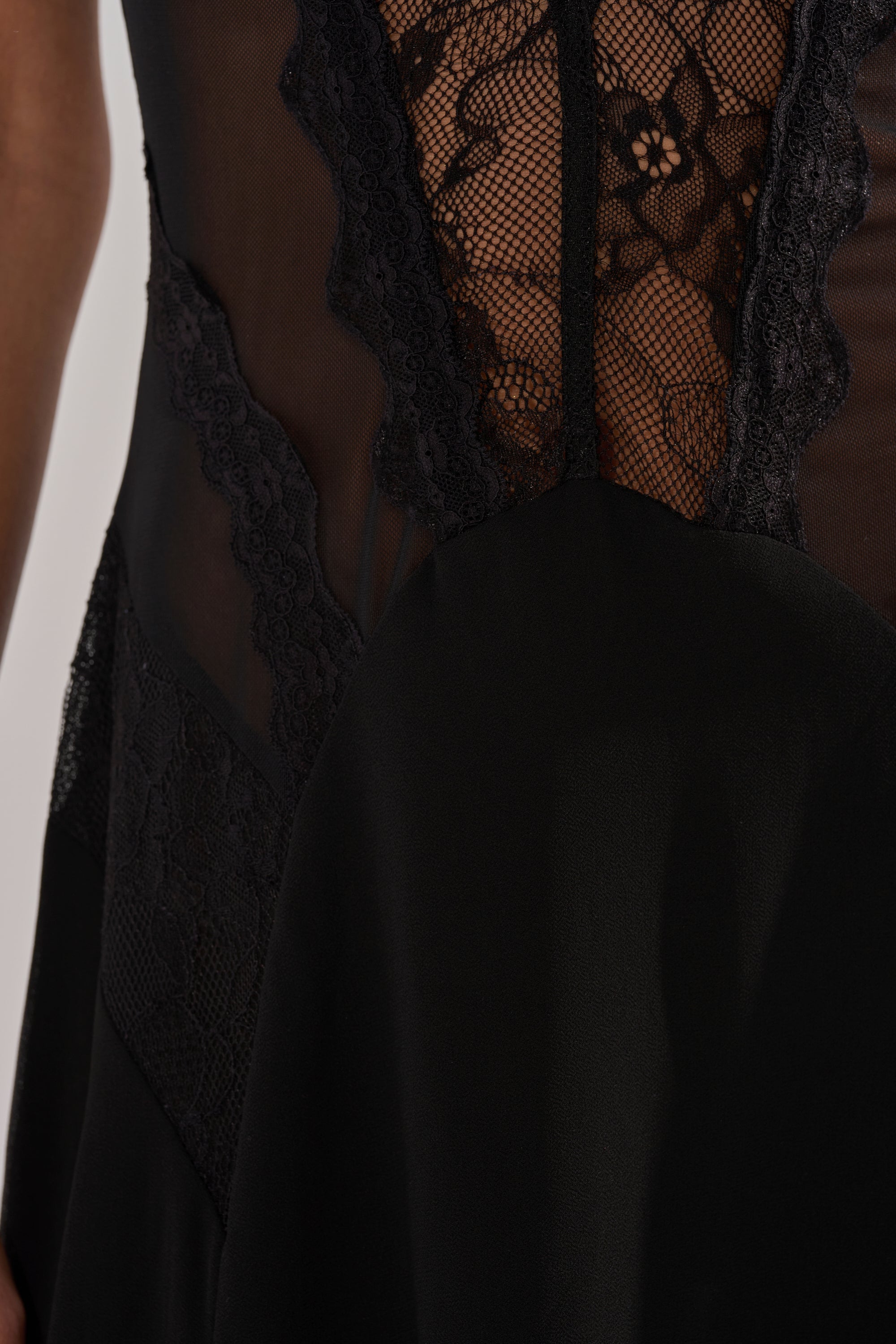 Close-up of the LEILA MAXI DRESS, a black maxi with a thigh-high slit, showcasing sheer mesh and floral lace panels that highlight the dress’s intricate details and elegant textures.