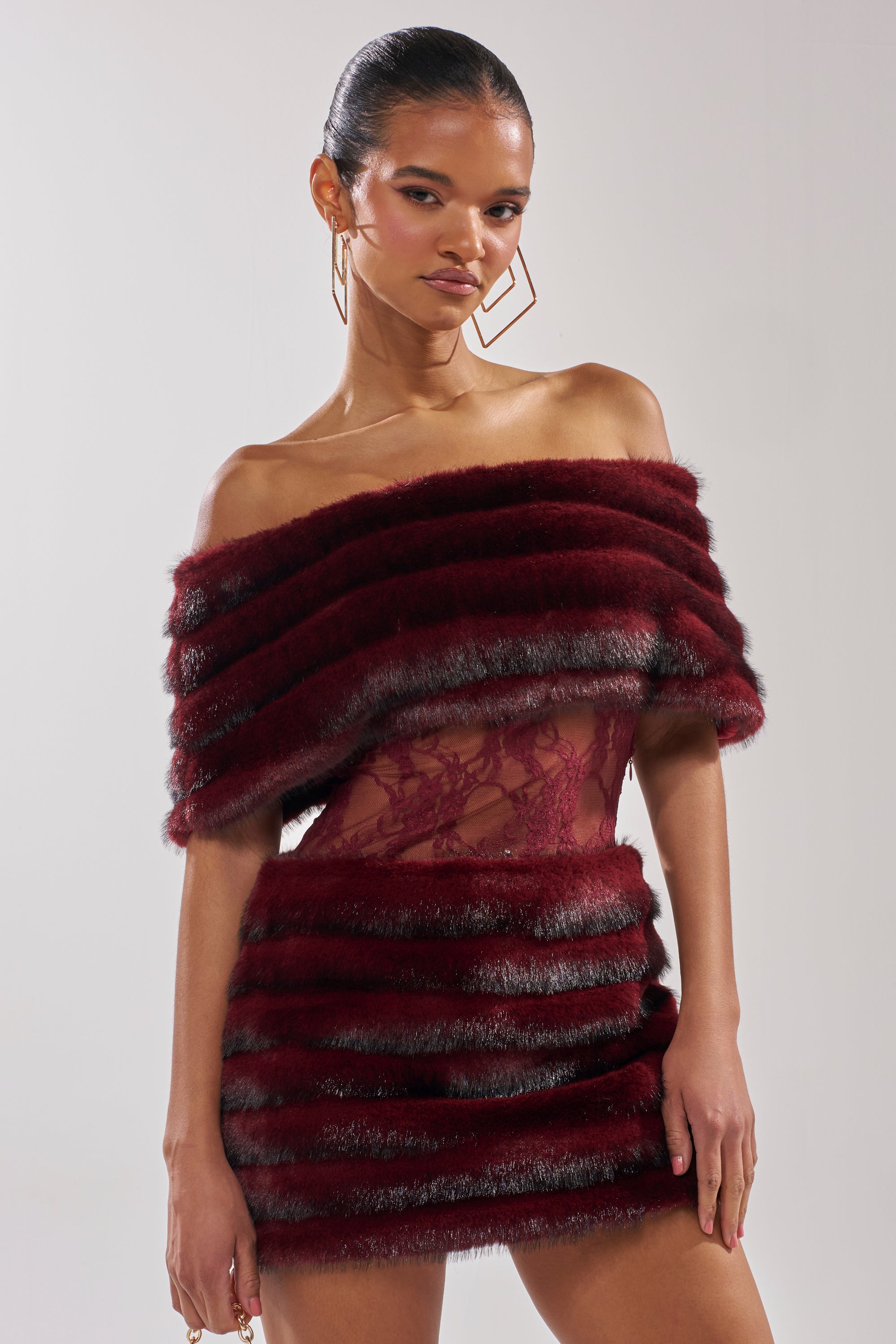 A woman poses in the SOFT CHERRY SLEEVELESS MINI DRESS, styled with large geometric earrings against a plain background.