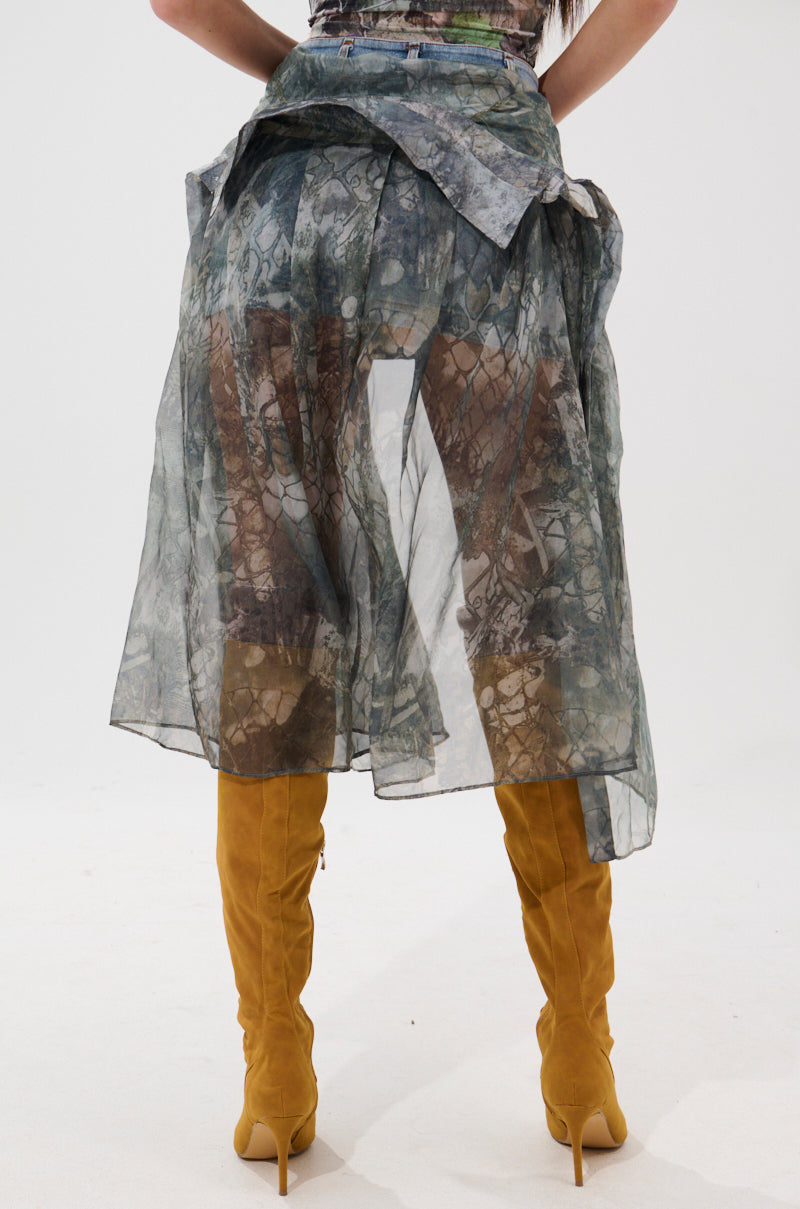 A person wearing the BRENDA DENIM MINI SKIRT WITH SIDE TIES, styled with mustard yellow knee-high heeled boots, photographed from the back against a plain white background.
