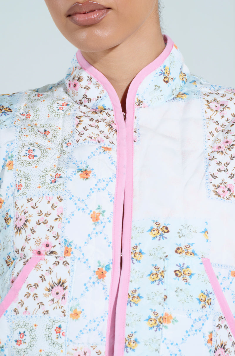 Close-up of a person wearing the Mixed Floral Puffer Vest with pink trim, exuding vintage feminine flair. The vest displays mixed floral patterns on a light background, focusing on the lower half of the face and upper body to highlight this elegant yet playful fashion choice.