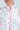 Close-up of a person wearing the Mixed Floral Puffer Vest with pink trim, exuding vintage feminine flair. The vest displays mixed floral patterns on a light background, focusing on the lower half of the face and upper body to highlight this elegant yet playful fashion choice.