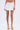 Wearing the LUCKY YOU EYELET MINI SKIRT with a floral eyelet design and high-rise fit, styled with beige platform sandals. The photo is cropped just above the waist and below the knees on a plain light background.
