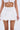 Wearing the LUCKY YOU EYELET MINI SKIRT with a high-rise fit and floral eyelet pattern, paired with a white lace-trimmed crop top, photographed from shoulders to thighs against a plain backdrop.