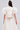 A woman faces away, wearing the GIRL POWER CROP TIE FRONT TOP—a cream satin piece with short, voluminous puff sleeves and a fitted waist. Her long dark hair is styled half-up, half-down.