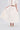 A person models the GIRL POWER MIDI SKIRT and a matching off-white, puff-sleeve crop top, holding out the skirt. Only their body and legs are visible; their face is not shown. The look is completed with embellished high heels.