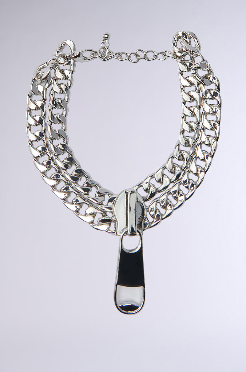 The ZIP IT ANKLET features a chunky silver chain with two thick links and a bold, modern metallic pendant at its center, showcased against a plain light background.