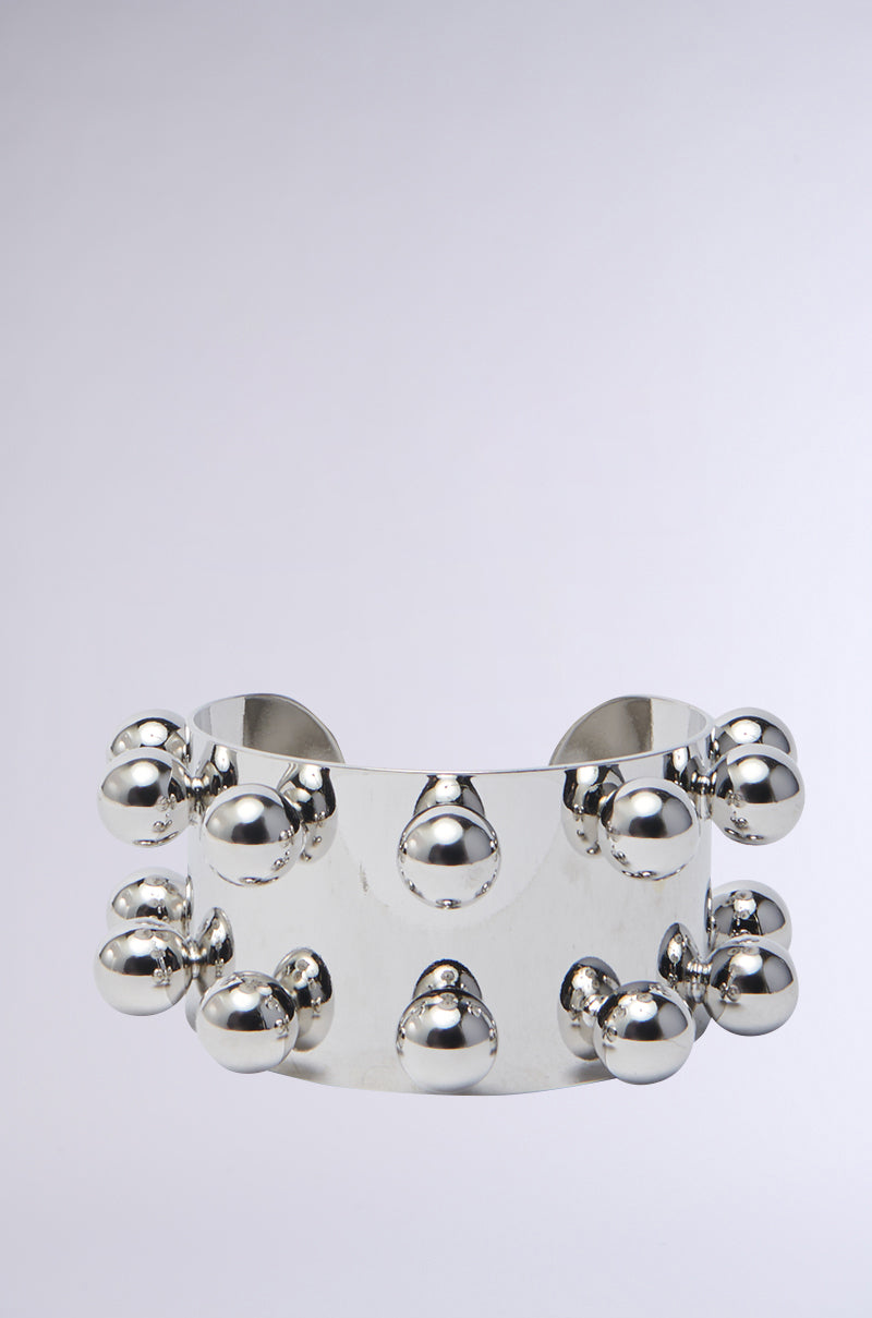 The WHAT A STUD SILVER CUFF is a wide, shiny faux silver bracelet featuring two rows of evenly spaced round beads—an effortlessly edgy accessory against a simple light gray background. 0