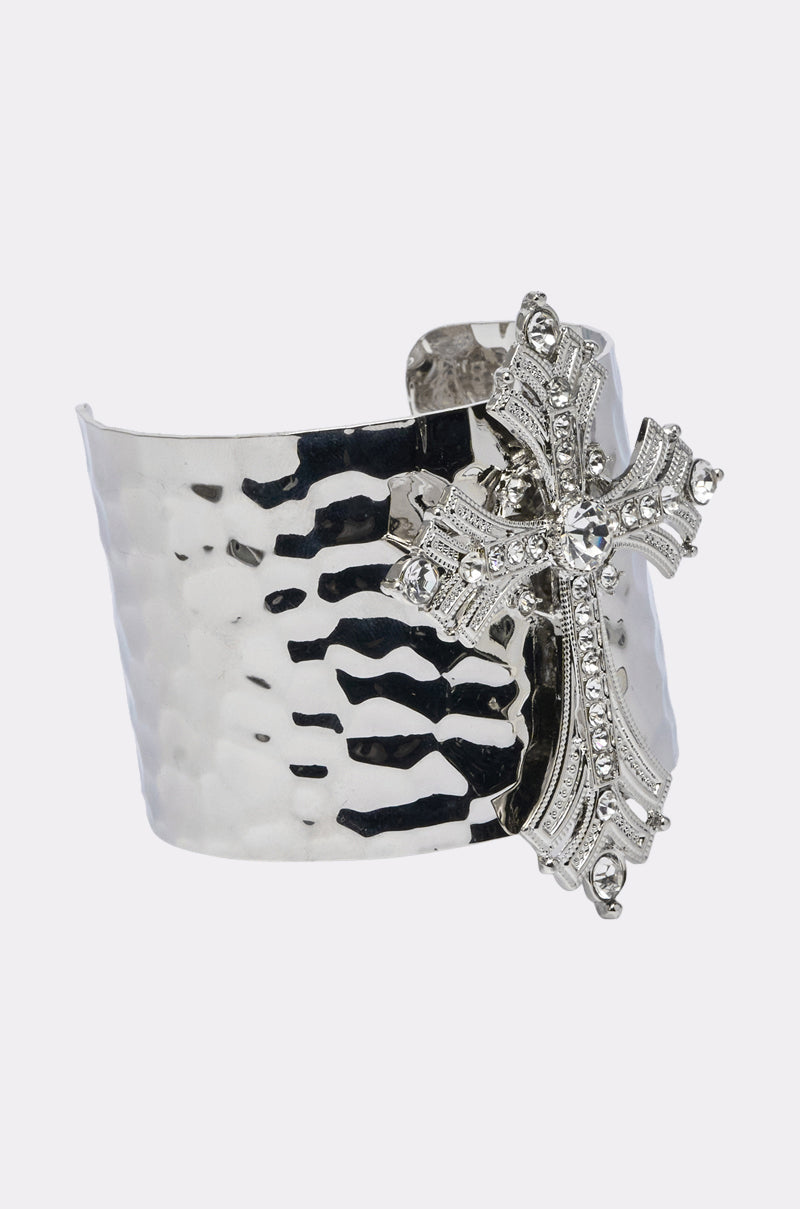 The GIVING ENERGY CUFF is a wide, hammered silver bracelet featuring a striking cross pendant embellished with sparkling rhinestones on one side. 2